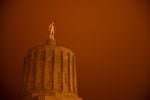 Wildfire smoke turns the sky orange at the Oregon Capitol in Salem. Officials say downed power lines ignited many smaller fires that helped the Santiam Creek Fire grow. 