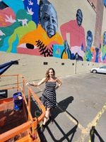 Executive Producer, Zoe Piliafas, stands in front of a colorful mural.