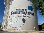 A reservoir painted with a cartoon airplane and globe paired with the words "Welcome to Pendleton Airport & Industrial Area"