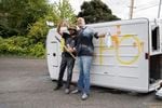 FILE - Dan Tooze, left, and Tusitala "Tiny" Toese stand in front of a flipped van after violent clashes with anti-fascist counterprotesters in Northeast Portland's Parkrose neighborhood on Aug. 22, 2021, in Portland, Ore.