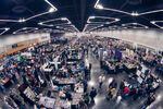 A view from the ceiling of a convention center shows dozens of people visiting booths on retro games and fandom.