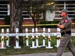 A police officer walks past a makeshift memorial for the shooting victims at Robb Elementary School in Uvalde, Texas, on May 26. The shooter in the attack legally purchased a gun before he turned 21.