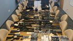 A table in a conference room is covered with guns and gun parts seized by law enforcement.