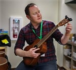 Librarian Brendan Lax tunes newly donated ukuleles to ensure they are ready for checkout.