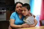 Rosalina Guzman sentada con su hijo menor en brazos. Ella y su esposo, Roman, tienen cinco hijos nacidos en los Estados Unidos.