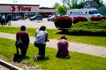 People pray outside the scene of a shooting at a supermarket, in Buffalo, N.Y., on Sunday. A day earlier, a white 18-year-old killed 10 people and wounded three in what authorities described as "racially motivated violent extremism."