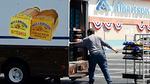 A bread salesman unloads a box truck with loaves of bread in front of an Albertsons grocery store.
