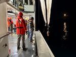 Crew members on the Bell M. Shimada drop a net into the ocean at night.