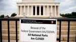 A sign posted in front of a stone monument reads "Because of the federal government shutdown all national parks are closed."