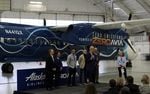 Politicians and corporate leaders gathered in a Paine Field hangar to celebrate the handover of a retired Alaska Airlines Q400 turboprop, which will be converted to hydrogen-electric propulsion over the next year.