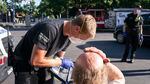A paramedic treats a man in a parking lot.