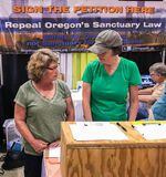 In this 2017 photo, Cynthia Kendoll, left, talks with volunteers at the Oregon State Fair booth of Oregonians for Immigration Reform. The group is gathering signatures for a proposed ballot measure that seeks to overturn the state's 30-year-old sanctuary law.