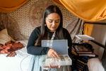 Megan Van Pelt leans on her dorm room bed while going through her dentalium shell collection which she uses for beading projects. Van Pelt says dentalium is meaningful to the Confederated Tribes of the Umatilla Indian Reservation.