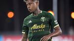 A male player wearing a green Portland Timbers soccer shirt that reads "Alaska Airlines" plays soccer.