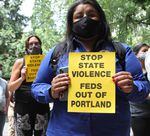 Protesters hold signs calling for federal law enforcement officers to leave Portland. 