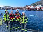 A group of local firefighters pose for a photo in Kungshamn, Sweden, on Sunday, as Hvaldimir swims in the water behind them.