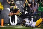 Oregon running back Travis Dye dives into the end zone over California safety Daniel Scott.