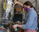 Wellspent Market’s Hannah Cable tips a drum of olive oil to fill a bottle at the Portland shop, Oct. 8, 2021. The store’s once yearly olive oil delivery from Italy has been stuck in transit for months. 