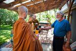 Ray Klebba, right, hands tea to Ajahn Kassapo on alms round. Klebba and his partner, Shelley Baxter, contribute food to the monks throughout the week.