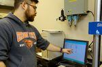 OSU researcher Byrne Miyamoto monitors how much weight a piece of Western Juniper can hold.
