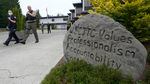 Police officers walk down a sidewalk. A large boulder next to the sidewalk is incribed with the words "WSCJTC values professsionalism accountability int --" the rest of the message on the rock is obscured by a bush.