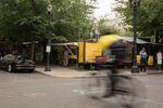 A bike whizzes by food pods on Southwest 10th Avenue and Alder Street in downtown Portland, Ore., on June 21, 2019. The pods must vacate the lot by the end of June to make room for a Ritz-Carlton.