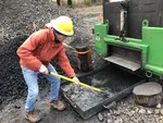 A forestry worker dredges out cooling bits of biochar released by the CharBoss outside Vida, Ore., March 7, 2023.