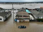 This aerial photograph shows a car and market shop in floodwaters in Pajaro, Calif., on Saturday. More rain and snow is expected in the state this week.