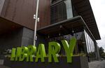 A sign in front of a building says "Library" in big green letters.