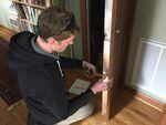 Peter Kernan of Enhabit measures the thickness of the insulation behind a wall as part of the home energy scoring process.