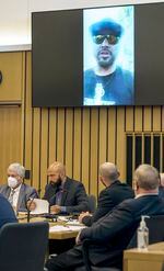 Video evidence of Joey Gibson plays above him, second from left, during the first day of trial, Monday, July 18, 2022, in Multnomah County Circuit Court. Gibson, Russell Schultz, III, and MacKenzie Lewis faced charges for allegedly instigating a street fight between Patriot Prayer and anti-fascists on May 1, 2019, at the now-closed bar Cider Riot.