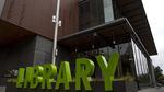 A sign in front of a building says "Library" in big green letters.
