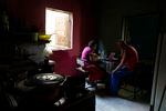 And elderly married couple eat lunch at a table together in a low-income home.