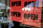 In this June 30, 2020, photo, a man passes a clothing shop with open signs in the window in Calexico, California. Records obtained by The Associated Press show governors working closely with business interests as they weighed when and how to reopen their economies during the coronavirus pandemic.