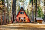 An A-frame house surrounded by large trees.