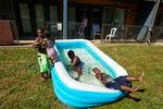 Jalen Askari, 7, right, plugs his nose as he falls into the pool he is playing in with his siblings, from left, Amari, 5, Bella, 2, and DJ, 10, in Portland, Ore., Tuesday, July 26, 2022. The temperature hit 102 that day, in the midst of the city's record streak of 95-plus degree days.