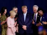 In this file photo from 2020, Pastor Paula White, left, and other faith leaders pray with President Donald Trump, center, during a rally for evangelical supporters at the King Jesus International Ministry church in Miami.