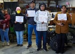 Several people stand in a garage holding signs urging action on Morrow County's nitrate crisis.