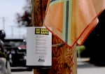At a crosswalk on Northeast Fremont Street, a container holds several bright orange flags and lists safety tips for pedestrians, Sept. 1, 2025. The flags were set up by the Beaumont-Wilshire Neighborhood Association to increase visibility on the busy street.