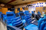 an empty gymnasium but it is filled with stacks of blue chairs and tables