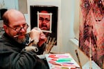 FILE - In this Jan. 3, 1996, file photo, Chuck Close, using a hand brace to hold his paint brush, adjusts the brush with his teeth while working in his New York studio. Since suffering a partial paralysis in 1988 due to a spinal artery collapse, Close does not have the strength to grip the brush. Close who is best known for his monumental grid portraits and photo-based paintings of family and famous friends, has died on Thursday, Aug. 19, 2021, at age 81.