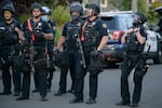 The Multnomah County District Attorneys Office is considering charges against another Portland Police Bureau Officer Thomas Clark, center with mask, stemming from last summer's protests. This photo shows Clark and another officer wearing gloves with hardened plastic knuckles. 