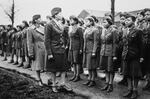 Commanding officers inspect troops, all women of color, standing outside.