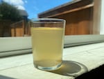 A hazy yellow glass of water on a window sill in the sun.