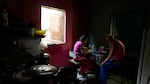 And elderly married couple eat lunch at a table together in a low-income home.