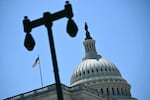 A view of the U.S. Capitol dome with a U.S. flag flying beside it.