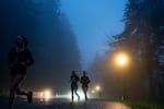 Runners jog through thick fog on a rainy evening in Southwest Portland, Ore., on Dec. 4, 2025.
