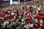 Alabama Crimson Tide football players, wearing white pants, red tops and red helmets, pose with fans  on September 19.