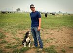 Justin Grant stands beside his border collie in his cow field in Midland on Aug. 5.