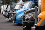 Semi-trucks, including an autonomous rig, far left, and one that’s both electric and autonomous, center, parked at the Daimler North American headquarters.